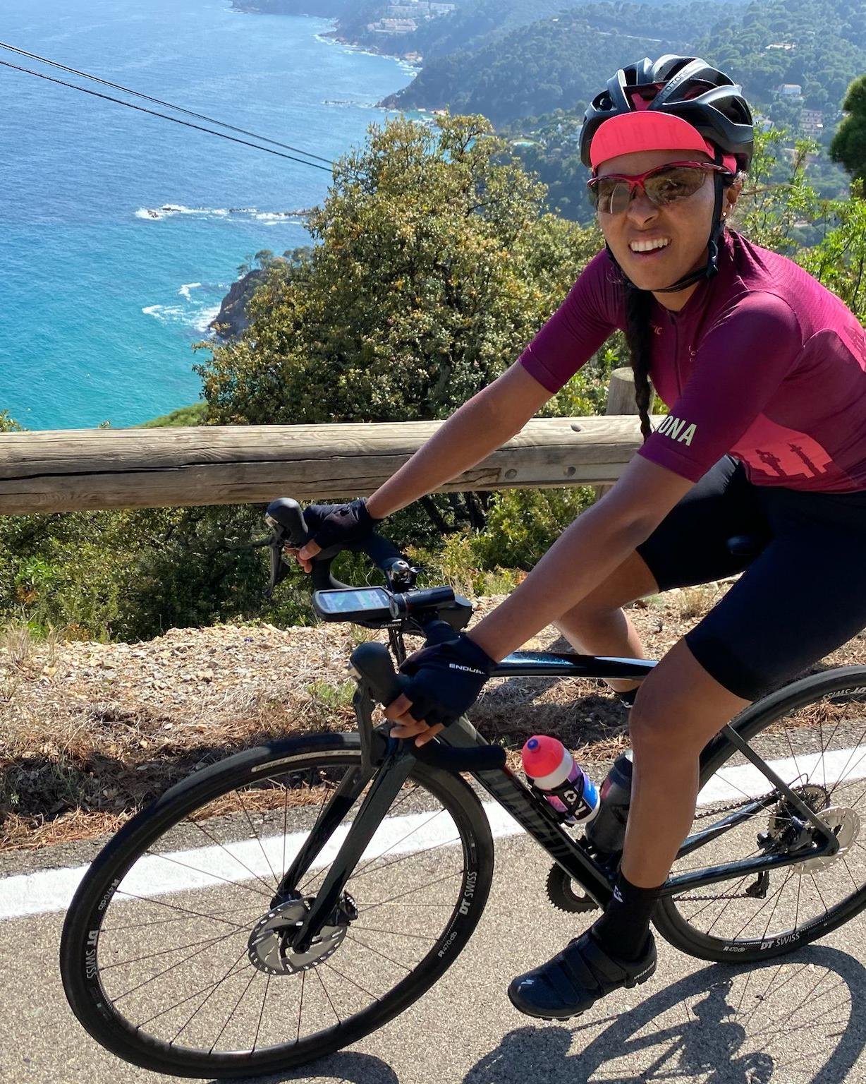 Daylin Miller cycles above the sparkling blue waters of Costa Brava, highlighting the stunning views available on Middle Ground Cycling’s road tours in Catalonia.