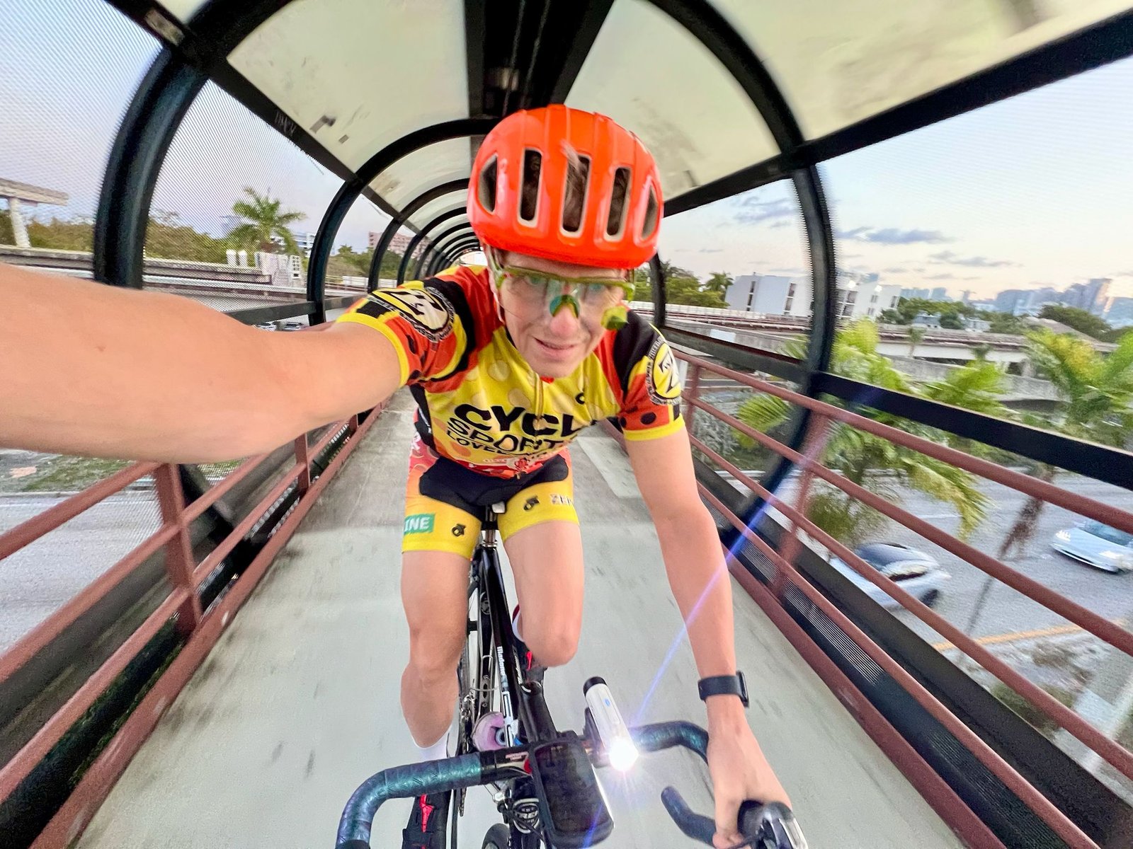 Jay Miller, co-founder of Middle Ground Cycling, rides confidently through a Girona overpass wearing a red helmet and custom cycling kit—showcasing his passion for guiding personalized bike tours in Catalonia, Spain.